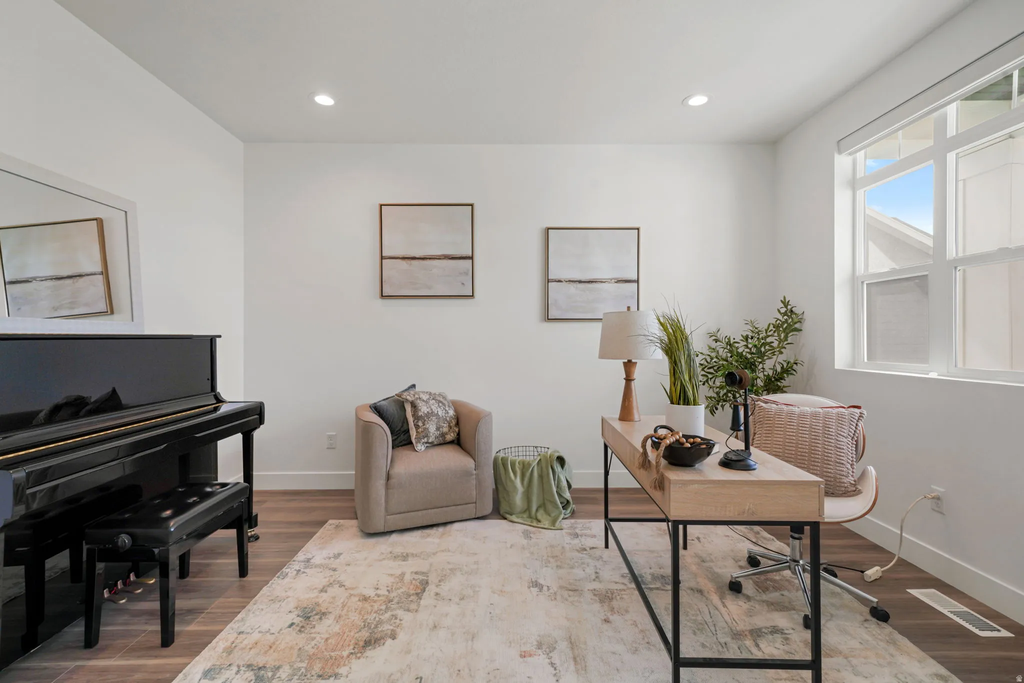 Bright, light-filled music room featuring a grand piano, hardwood flooring, and large windows with natural light