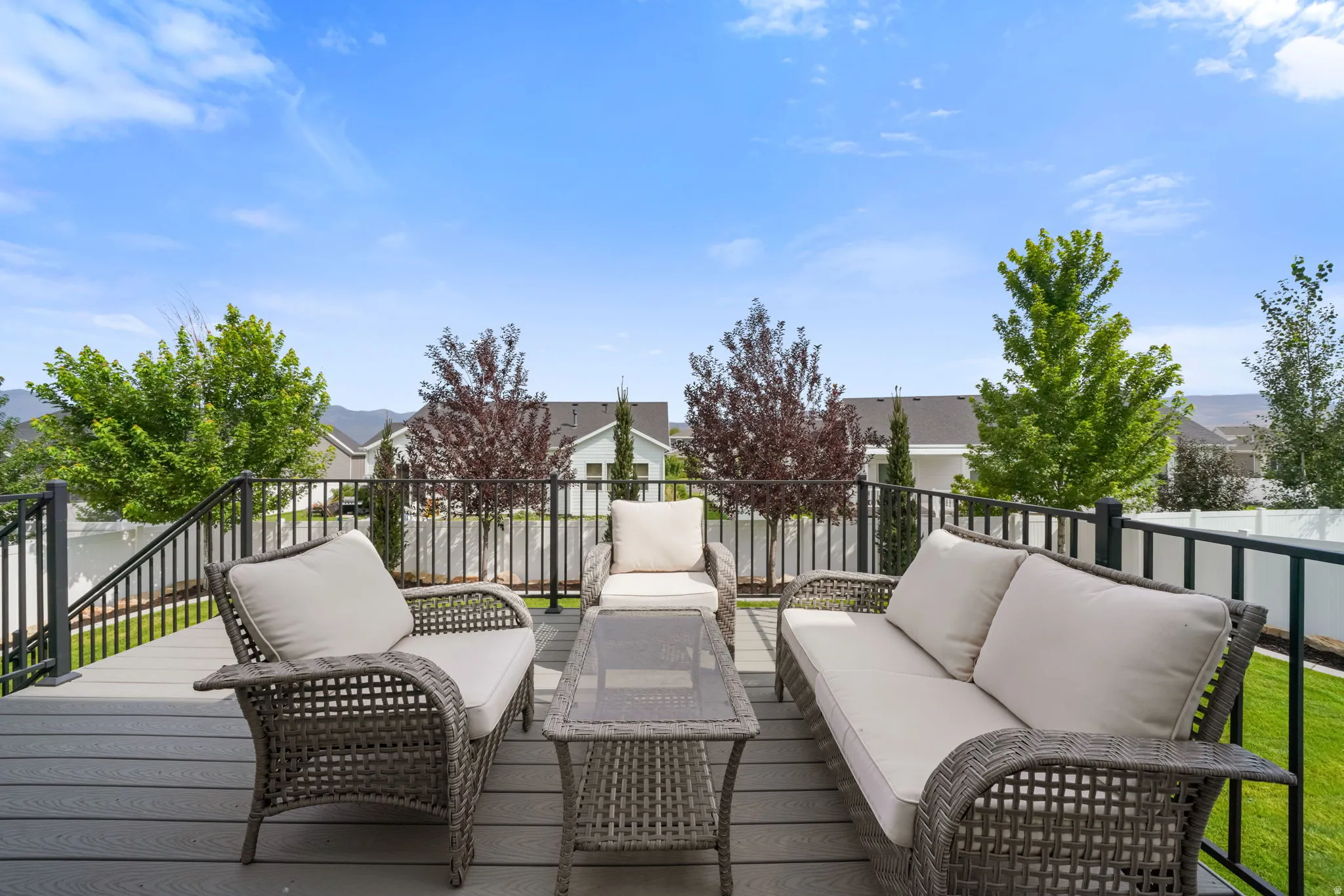 Expansive composite deck featuring composite decking with integrated metal railings, multiple seating zones, and a central glass-top table