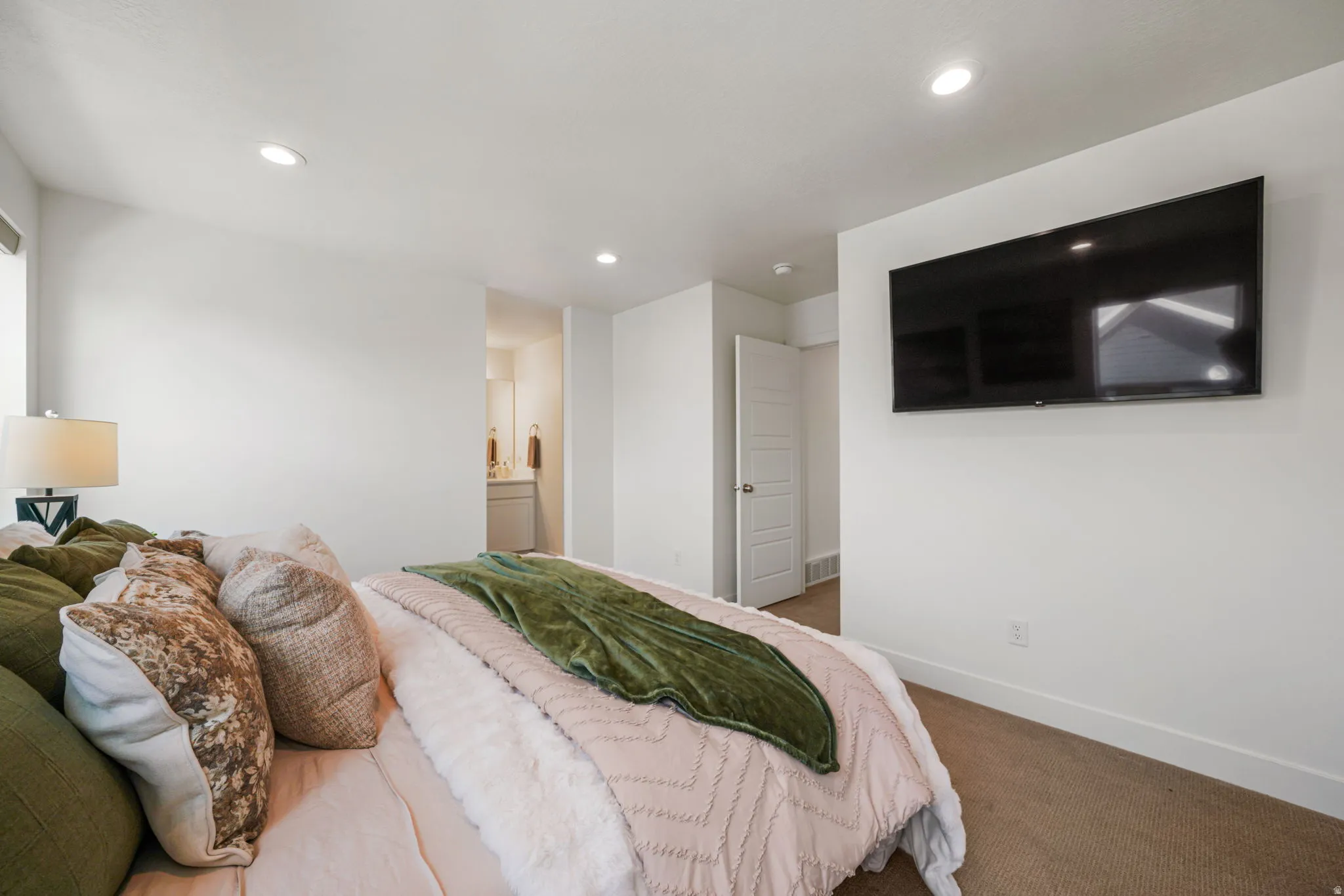 Primary Bedroom featuring recessed ceiling lighting, wood-finish flooring, wall-mounted flat-screen television, and ensuite bathroom access