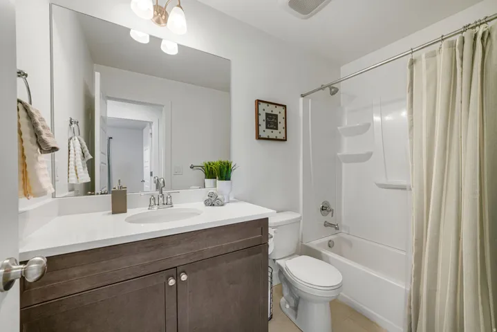 Spa-inspired bathroom featuring a dark wood-finish vanity with dual handles, white quartz countertop, and chrome faucet