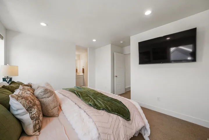 Primary Bedroom featuring recessed ceiling lighting, wood-finish flooring, wall-mounted flat-screen television, and ensuite bathroom access
