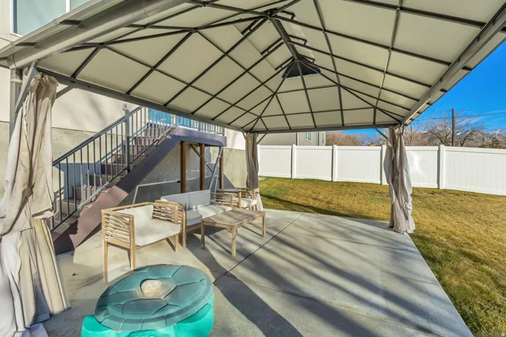 Covered patio area with a concrete slab and direct stair access to an upper level