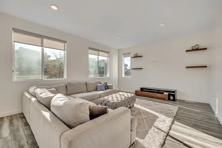 White walls with recessed lighting, multiple windows, wood-finish flooring, and wall-mounted shelving