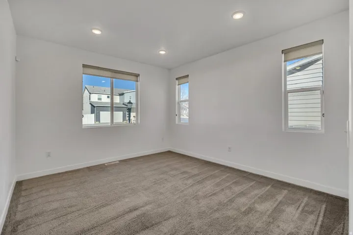 Recessed lighting, multiple windows, neutral wall color, and plush carpeting