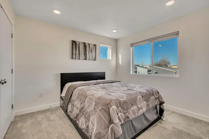 Recessed lighting, light gray carpeting, and white walls create a neutral palette