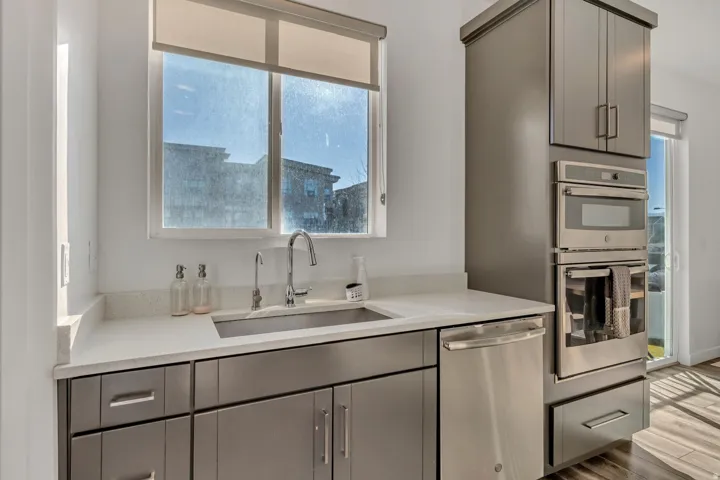 Stainless steel appliances, built-in oven, integrated microwave, undermount sink, and light-toned countertops