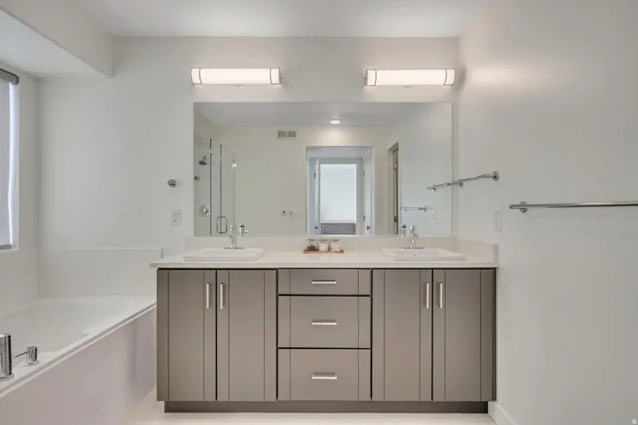 Double vanity with undermount sinks, light-toned countertop, and gray cabinetry