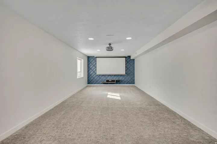 Spacious room with recessed lighting, wall-mounted projection screen, ceiling-mounted projector, and patterned accent wall