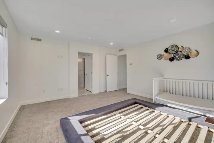 Recessed ceiling lighting, light gray wall paint, light gray carpeting, window with roller shade, and white trim throughout