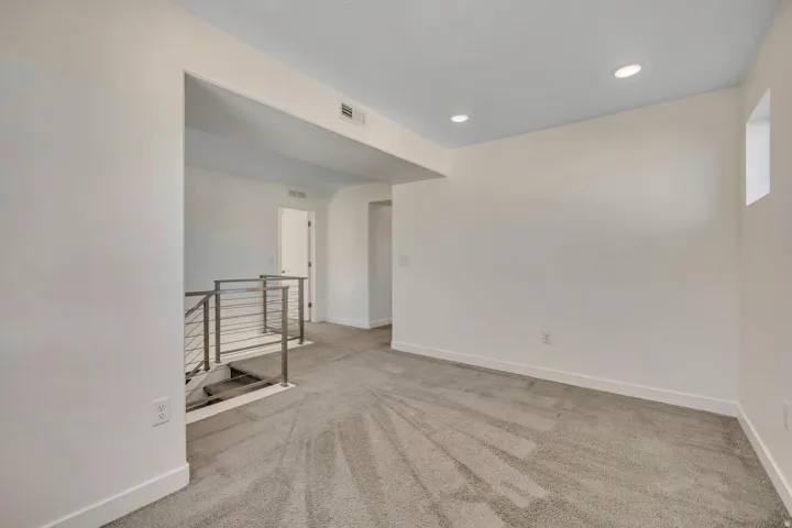 Carpeted room featuring recessed lighting, a small window, and a staircase with metal railings