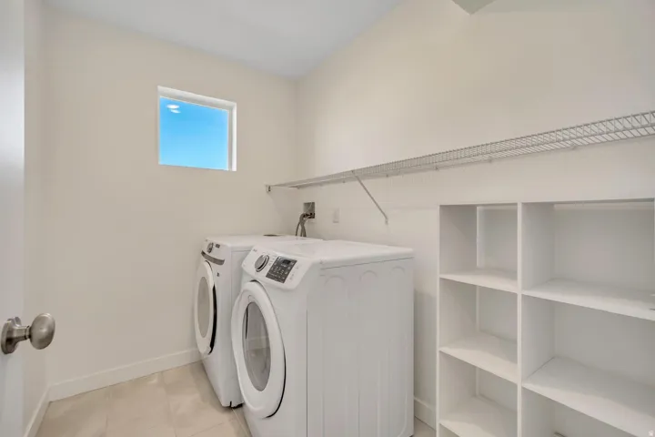 Laundry room with a window, white walls, built-in shelving, and wire rack storage
