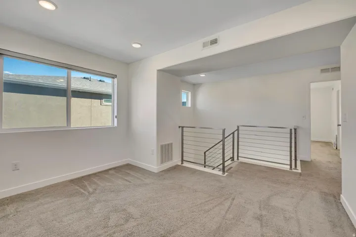 Upper-level landing featuring neutral carpeting, a large window, recessed lighting, and modern metal railings