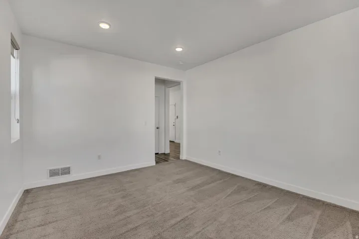 Recessed lighting, neutral-toned walls, and carpeted flooring