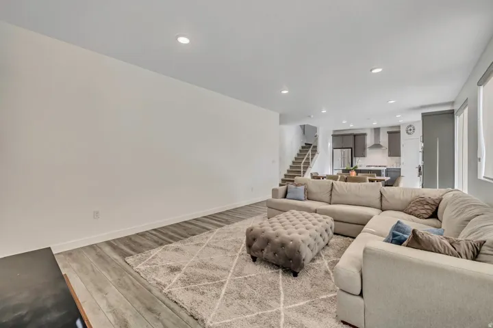 Recessed lighting, wood-finish flooring, staircase with natural wood treads, and contemporary kitchen cabinetry