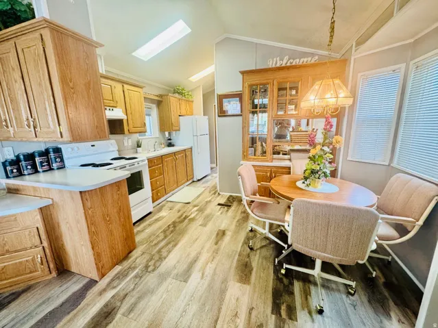 Kitchen featuring wood-finish cabinetry, white appliances, and wood-finish flooring