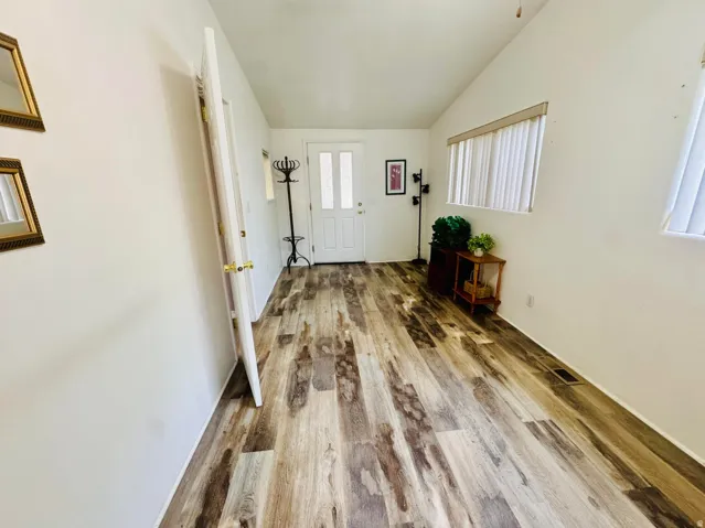 Wood-finish flooring throughout, white walls, and a white entry door with frosted glass panels