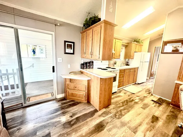 Kitchen featuring wood-finish flooring, wood cabinetry, white appliances, and a sliding glass door