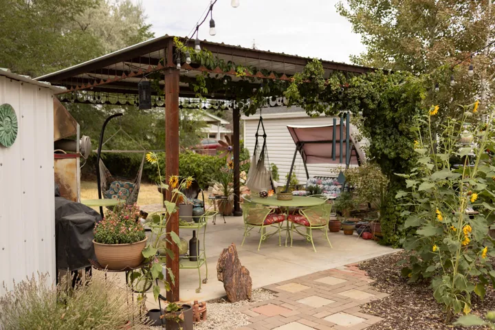 Expansive patio area featuring a metal pergola with string lighting, concrete slab, and a paver pathway