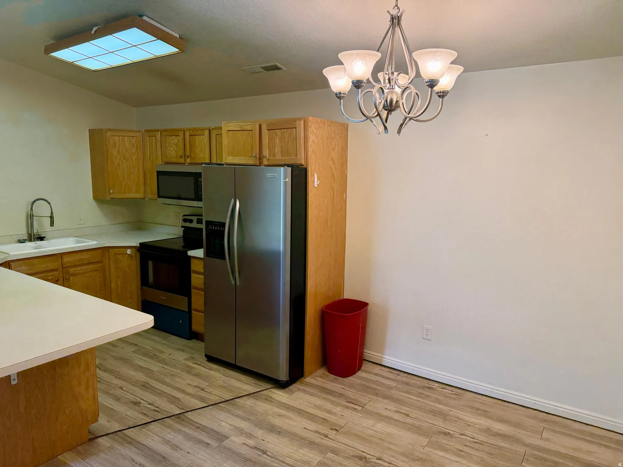 Kitchen featuring wood-finish flooring, wood cabinetry, stainless steel appliances, and a peninsula countertop