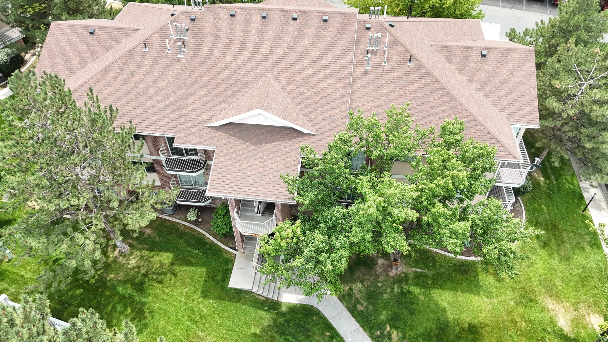 Multi-story building featuring a brown shingle roof, brick facade, and multiple balconies