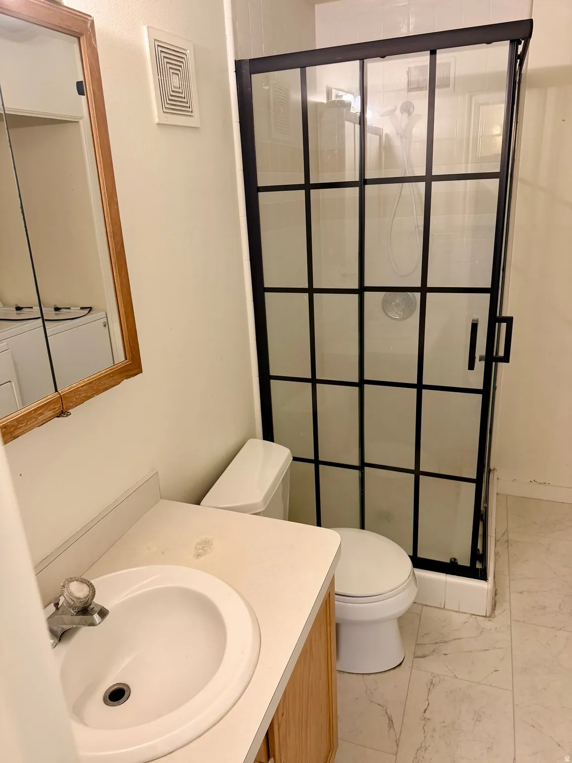 Enclosed shower with black grid-pattern glass door