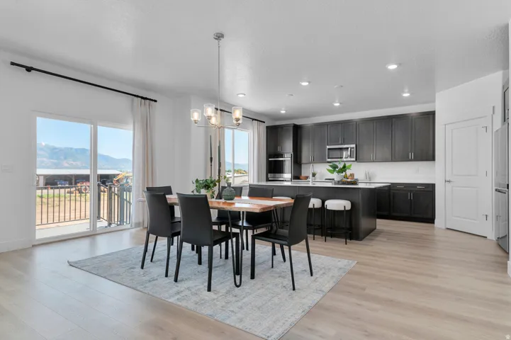 Open-concept layout featuring a kitchen with dark cabinetry, stainless steel appliances, and a central island with bar seating