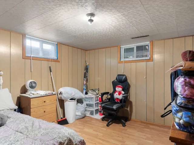 Wood-finish flooring with paneled walls, two windows, and a flush-mount ceiling light fixture