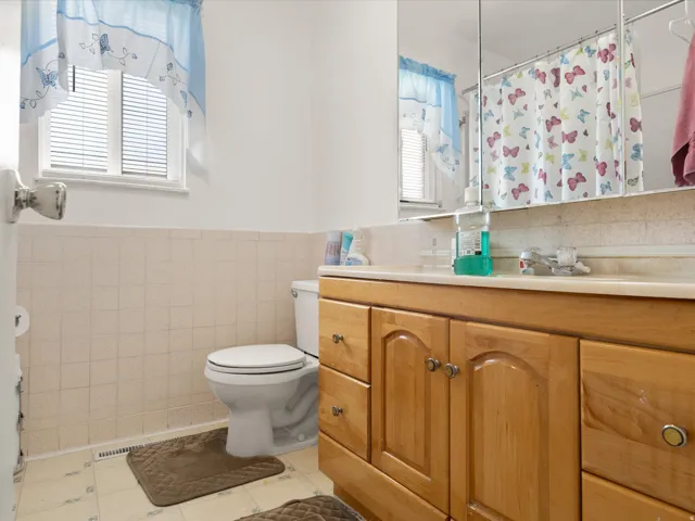 Wood-finish vanity with ample storage, integrated countertop, and tiled walls