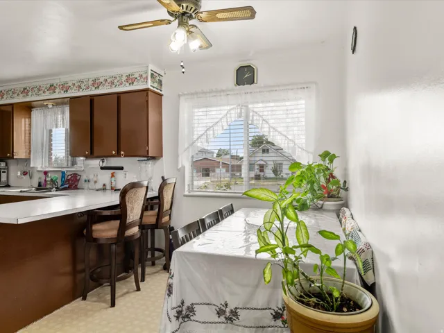 Kitchen and dining area featuring brown cabinetry, a functional breakfast bar, and a ceiling fan with integrated lighting