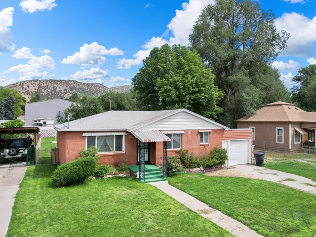 Brick exterior with white trim, covered front porch, attached garage, and a lush green lawn