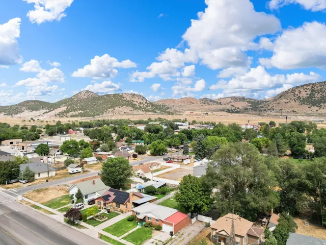 Aerial perspective showcasing a residential area with established homes, mature trees, and mountainous terrain in the background