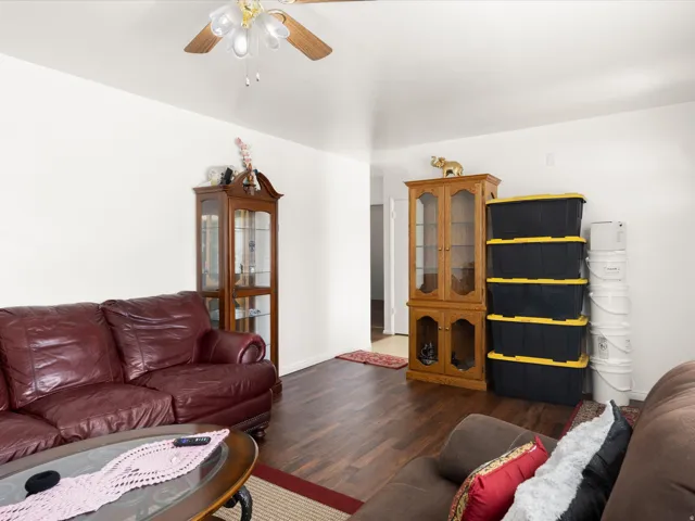 Wood-finish flooring with white walls and a ceiling fan with integrated lighting