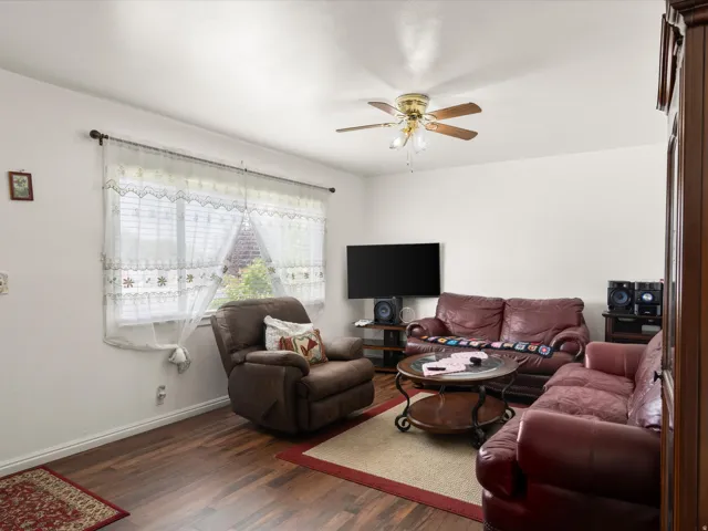 Wood-finish flooring, ceiling fan with integrated lighting, and a large window