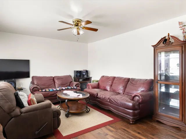 Wood-finish flooring throughout, complemented by light-toned wall paint and a ceiling fan with integrated lighting