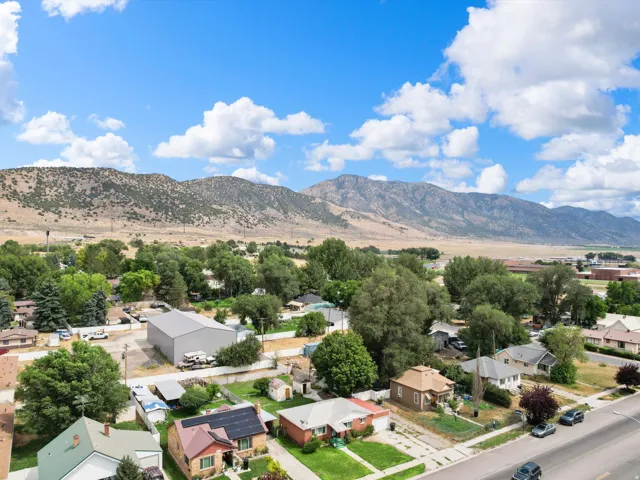 Mountainous terrain, residential properties, established trees, paved street, and utility infrastructure