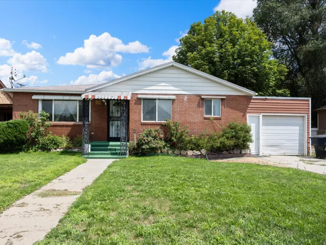 Brick exterior with an attached garage, covered entry, and front yard