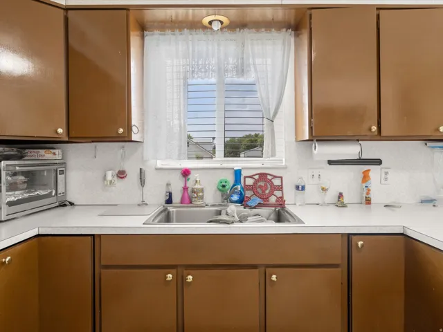 Kitchen featuring brown cabinetry, white countertops, double basin sink, and a window