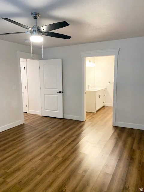 Wood-finish flooring, a ceiling fan with integrated lighting, and white paneled doors