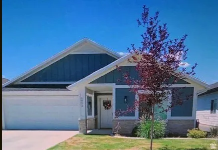 Blue facade with white trim, stone veneer accents, an attached garage, and a covered entry