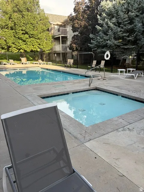 Outdoor swimming pool with integrated spa and surrounding concrete decking