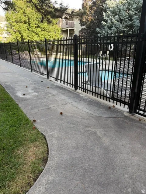 Outdoor swimming pool with black metal fencing and a curved concrete pathway