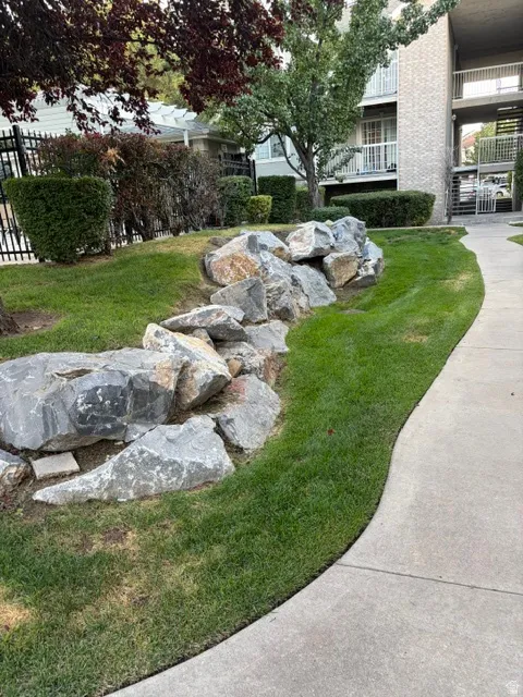 Curved concrete pathway with an adjacent rock garden and manicured lawn