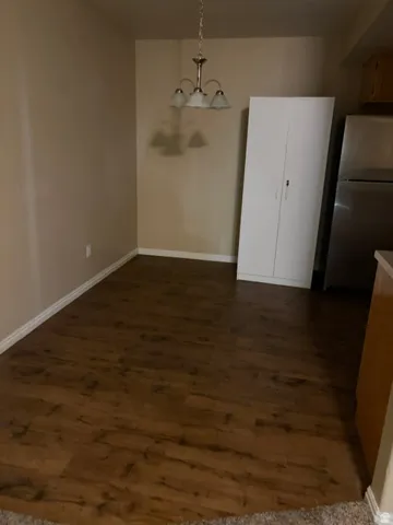 Recessed dining area with a three-light chandelier and wood-finish flooring