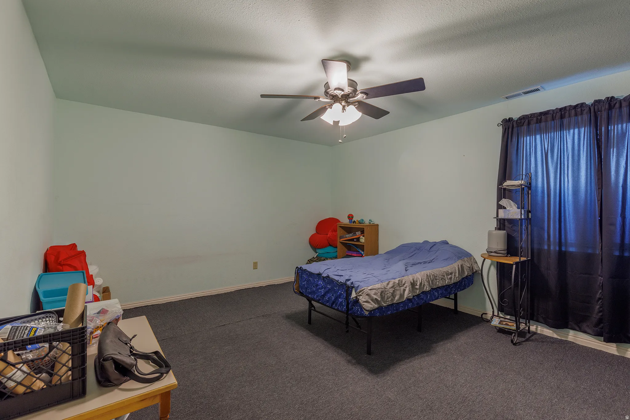 Room featuring light green walls, dark textured carpeting, and a ceiling fan with integrated lighting
