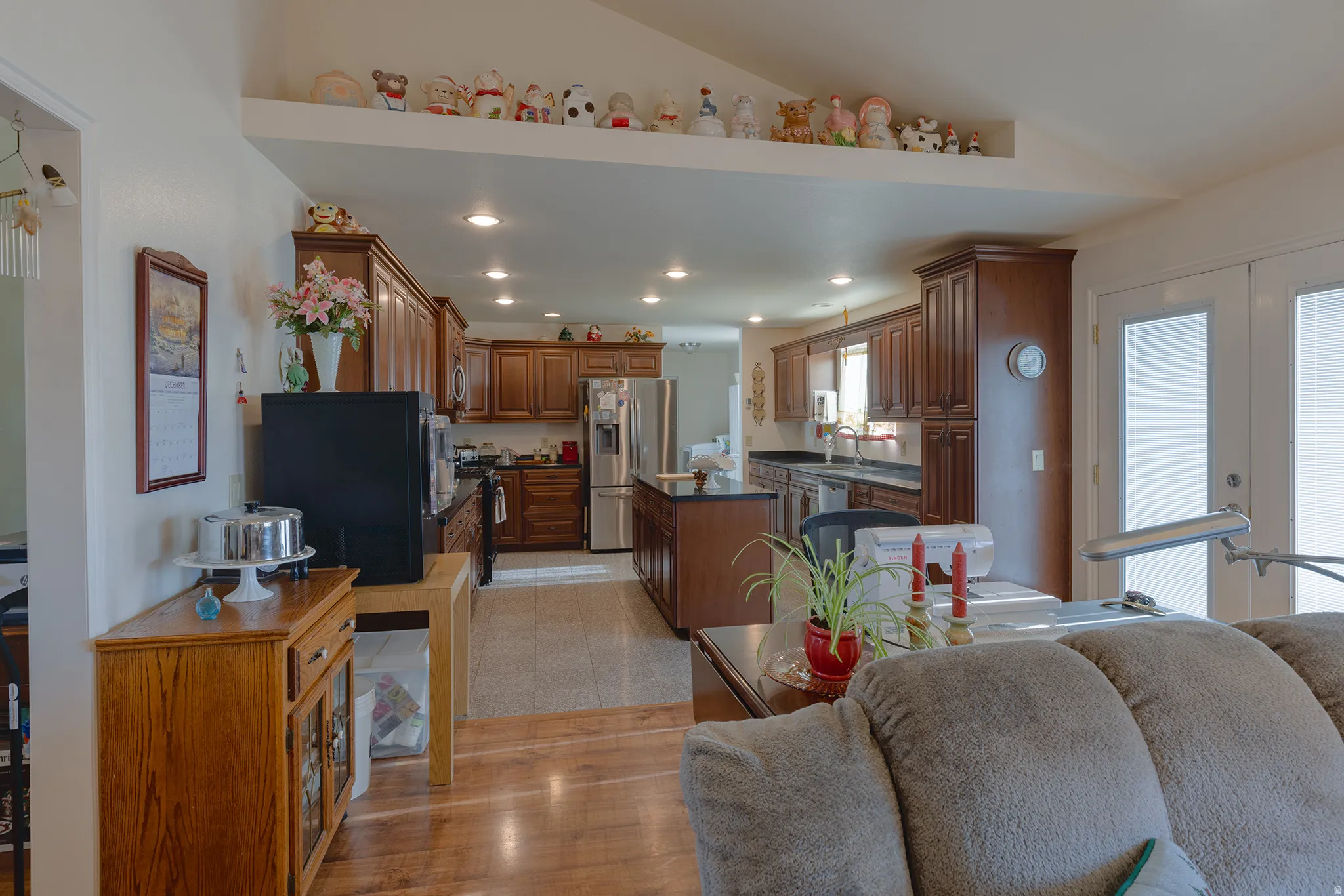 Open-concept living area with wood-finish flooring, vaulted ceiling, recessed lighting, and double glass-paneled doors