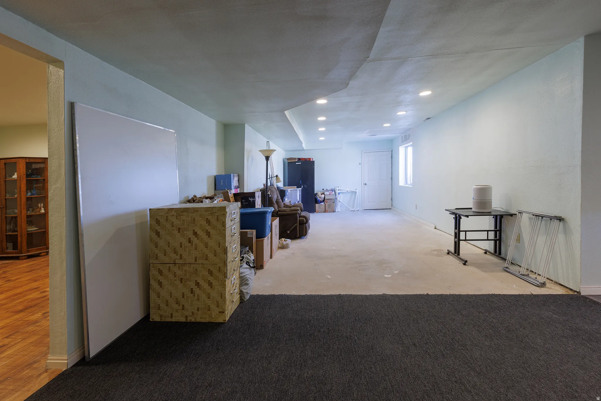 Spacious open floor plan featuring recessed ceiling lighting, neutral wall finishes, and a combination of dark tile and wood-finish flooring throughout