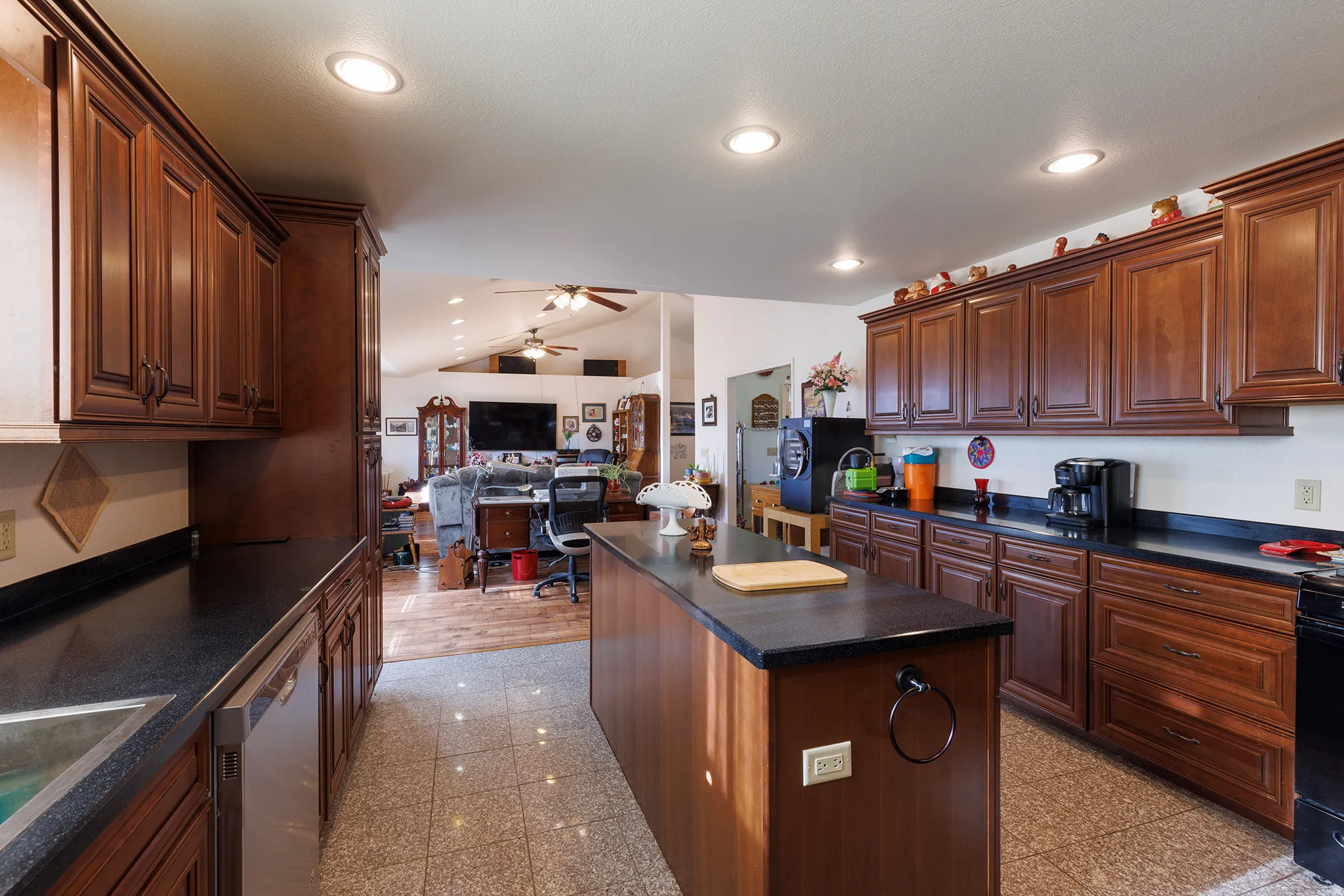 Kitchen featuring extensive wood-finish cabinetry, dark countertops, recessed lighting, and a center island