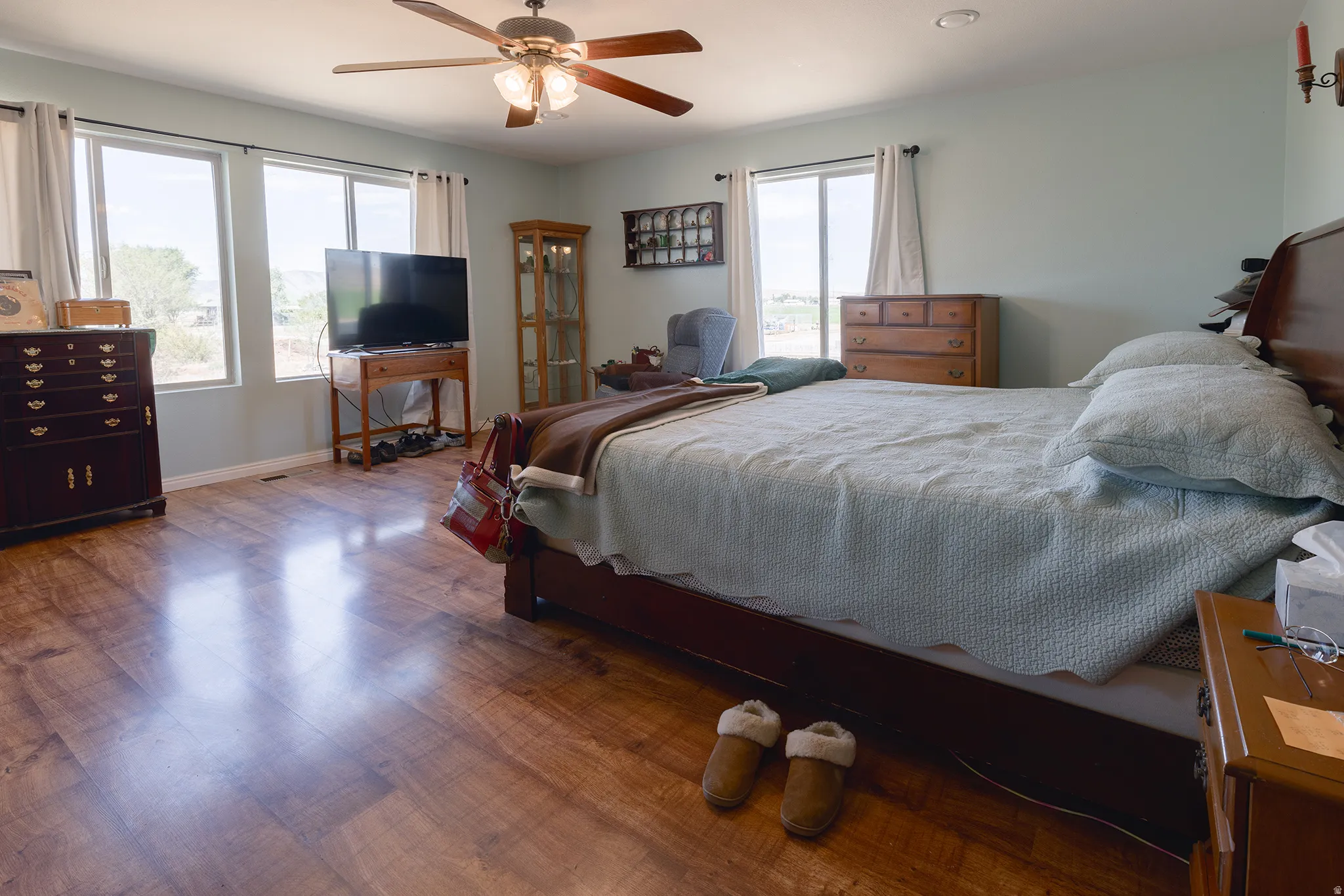Wood-finish flooring, multiple windows with natural light, ceiling fan with integrated lighting, recessed lighting, and light-toned wall paint