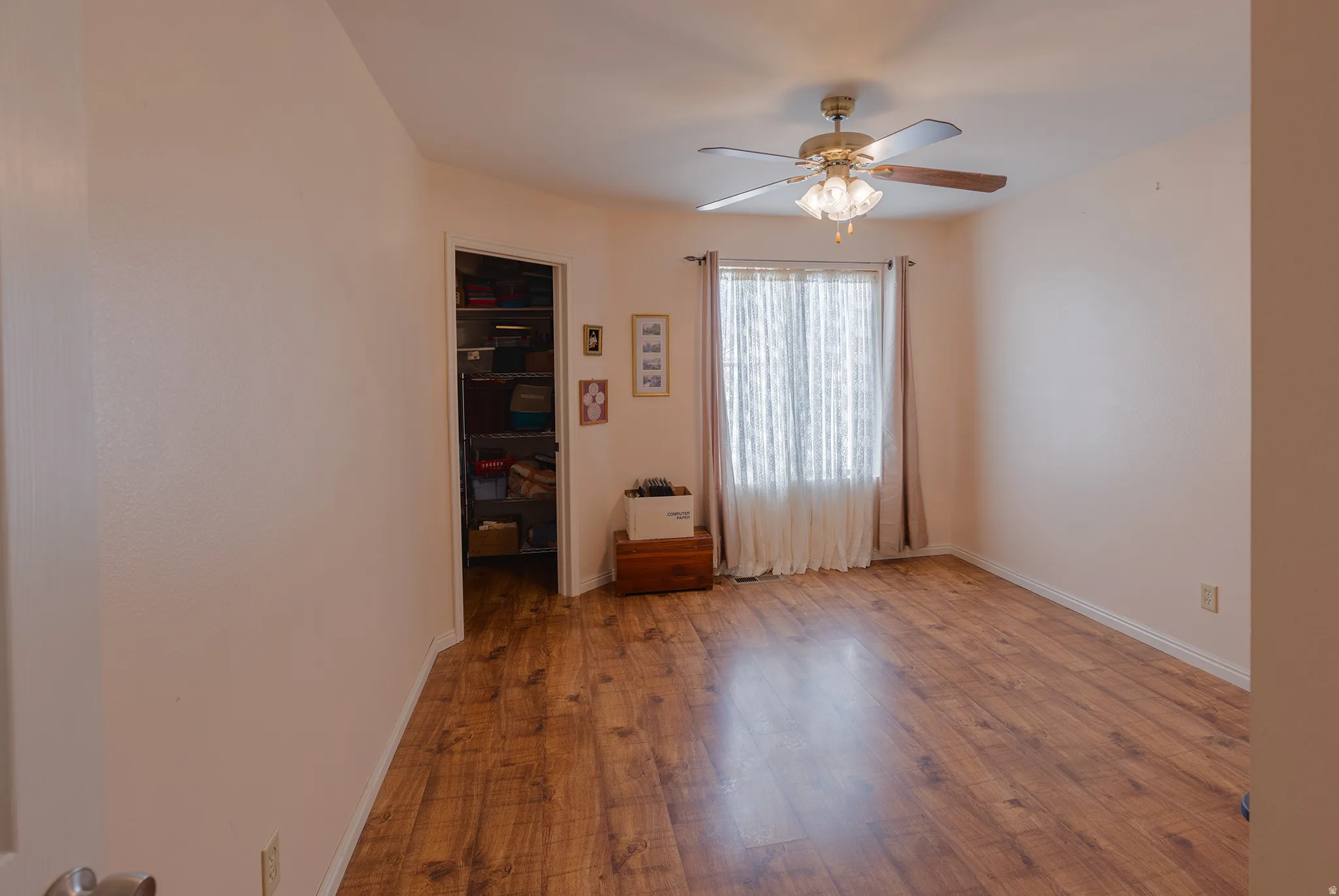 Wood-finish flooring, ceiling fan with integrated lighting, and a single window