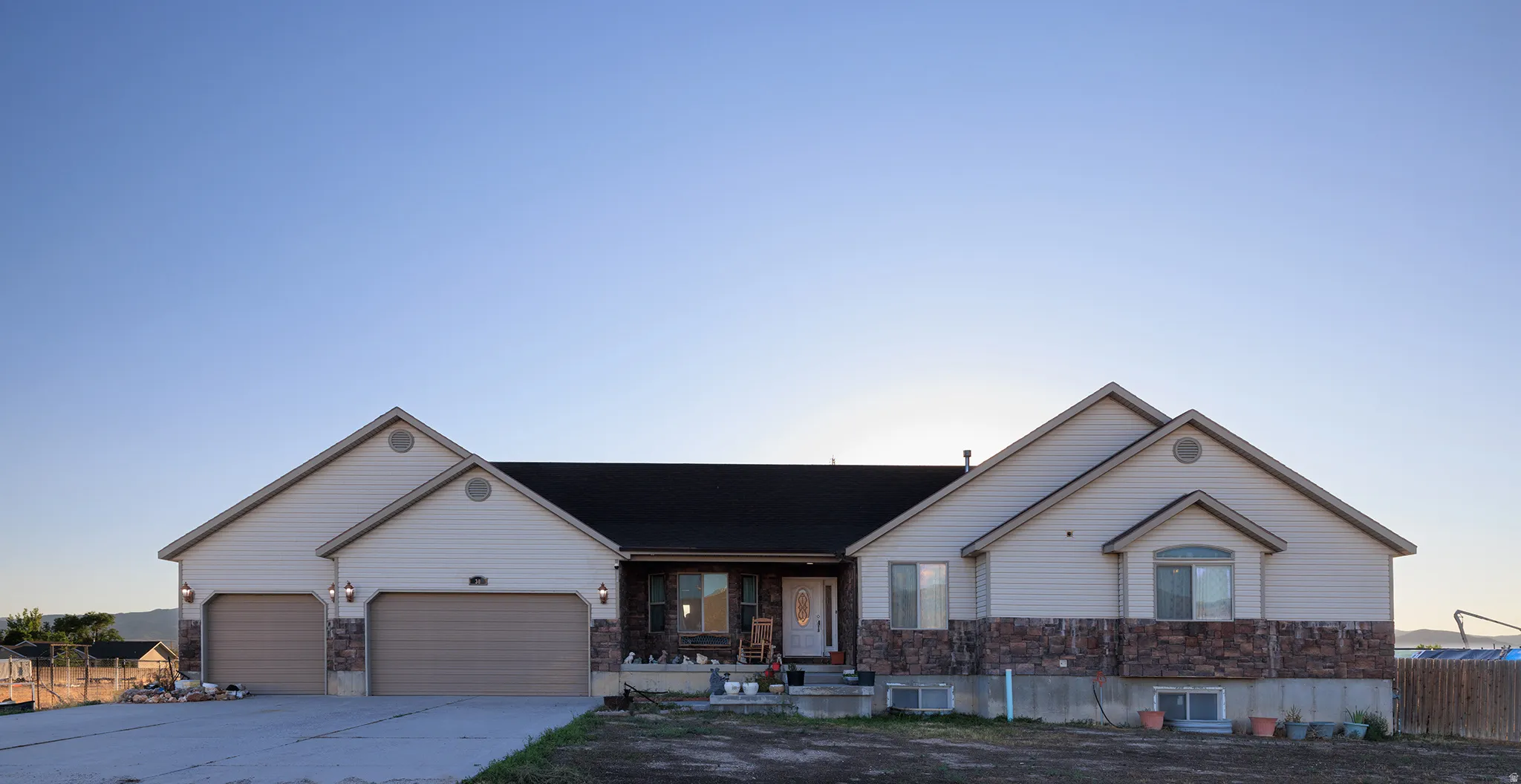 Siding exterior with stone accents, covered front entry, two-car garage, and multiple gables